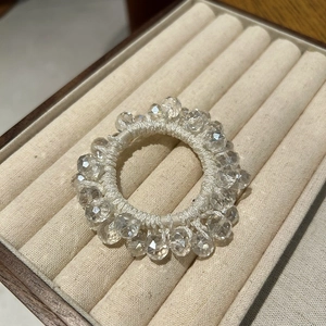 Detail of high-quality elastic hair tie with faceted crystal beads on beige velvet tray