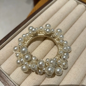 Detailed macro view of an elegant pearl scrunchie resting on a beige velvet jewelry tray