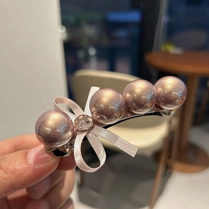 Gros plan d'une barrette en perles or rose avec un élégant nœud en satin et strass brillant