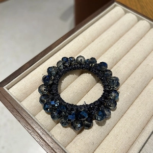 Detail of dark blue crystal beads hair tie on velvet jewelry display tray