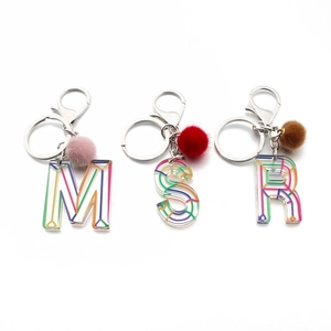 Macro view of acrylic letter keychains with colorful patterns and soft fur pompom decor