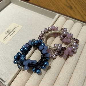 Dettaglio degli elastici per capelli intrecciati con perle di cristallo blu e viola su vassoio