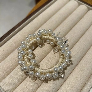 Close-up of elegant pearl hair tie with white imitation pearls and transparent acrylic beads
