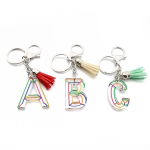 Detail of acrylic alphabet A B C keychains with rainbow lines and colorful tassels