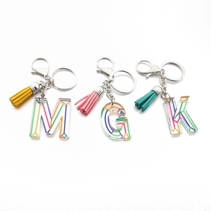 Acrylic alphabet keychains with colorful tassel and geometric rainbow patterns on white base