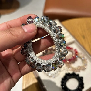 Detail of beaded hair tie with iridescent grey faceted crystals and elastic band