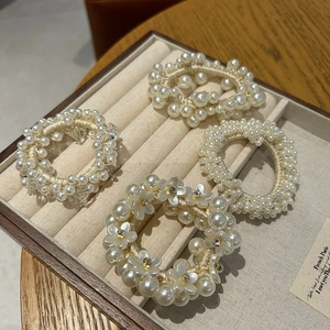 Detailed view of elegant pearl hair ties and camellia flower scrunchies in a jewelry tray