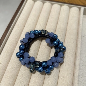 Dettaglio macro dell'elastico per capelli con perline di cristallo blu su velluto