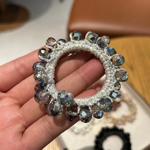 Close-up of a silver-grey elastic hair tie with sparkling crystal beads held in hand