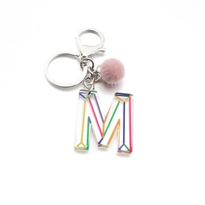 Detail of acrylic letter M keychain with pink faux fur pompom and metal clasp