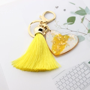 Detail of yellow heart resin keychain with golden glitter and elegant fringe tassel