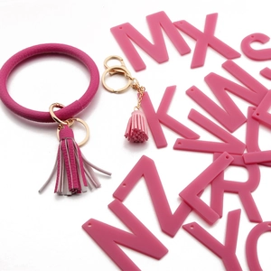 Detail of rose red PU leather O-ring bracelet with tassel and acrylic letter charms