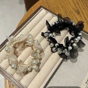 Detailed view of elegant pearl and mesh camellia hair ties on a velvet jewelry tray