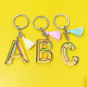 Detail of acrylic alphabet A, B, C keychains with colorful tassel and metal ring