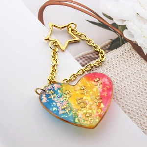 Macro detail of rainbow resin heart keychain with golden roses and star clasp