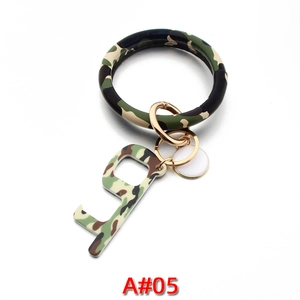 Detail of camouflage leather bracelet keychain with gold hook and acrylic door opener