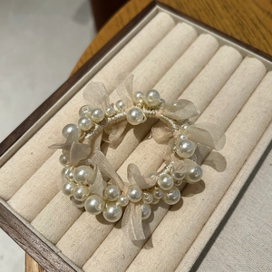 Detailed view of white pearl hair scrunchie with soft tulle bow on jewelry tray