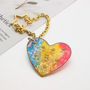 Macro shot of a heart-shaped glitter resin keychain with gradient colors and gold charms