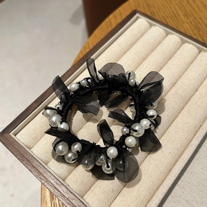 Detailed macro view of black lace mesh scrunchie with layered white pearls and elastic band