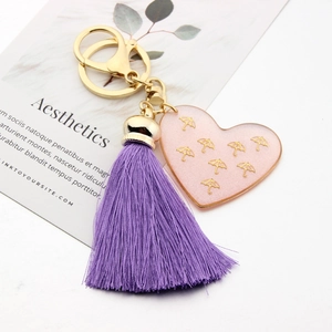 Detail of pink resin heart charm with gold pattern and soft purple tassel keychain