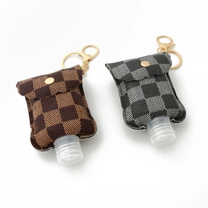 Close-up of checkerboard PU leather hand sanitizer holders with golden keychains