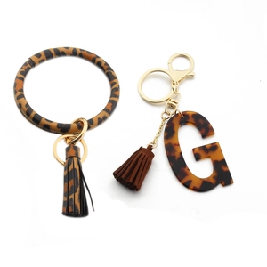 Detailed macro view of leopard print PU leather bangle with a gold G-letter keychain