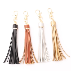Detail of four PU leather tassel keychains in black, brown, white, and gold finishes