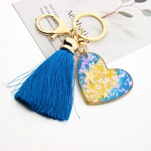 Detail of a blue gradient resin heart keychain with silk tassel and golden star sequins