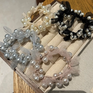 Close-up of elegant pearl mesh hair scrunchies in four colors on a jewelry display tray