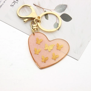 Detailed macro view of heart-shaped resin keychain with glitter and golden butterfly charms