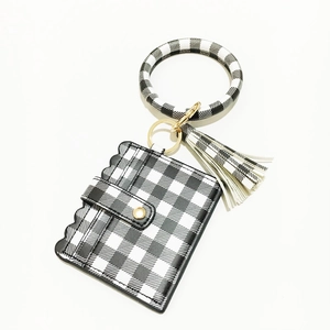 Detail eines Kartenhalters mit Gingham-Muster, goldenem Armreif und Fransen-Anhänger