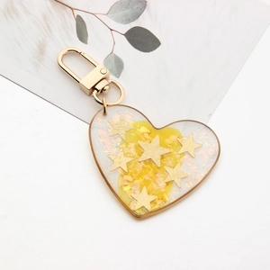 Detailed view of heart resin keychain with gold stars and glitter on a white background
