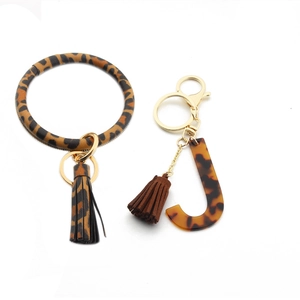 Detail of leopard print PU leather bracelet and acrylic letter J pendant keychain