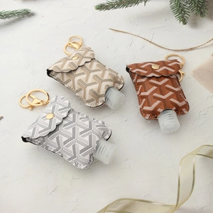 Three travel size PU leather bottle sleeves with keychains on festive textured background