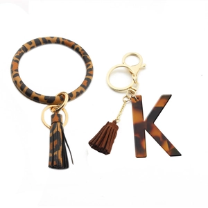 Close-up of leopard print PU leather wristlet with tortoiseshell acrylic letter K pendant