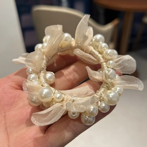 Close-up of pink organza bow hair scrunchie with white pearls held in a hand