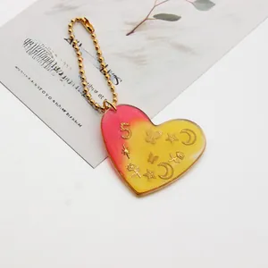 Macro shot of heart resin keychain with gold glitter butterfly and number five detail