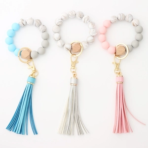 Detailed close-up of silicone and wood bead keychains with long tassels in three soft colors