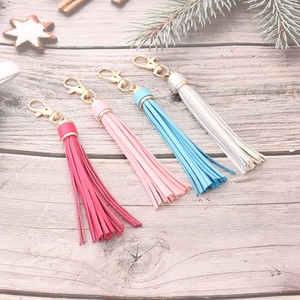 Set of four colorful PU leather tassel keychains with gold metal hooks on wood background