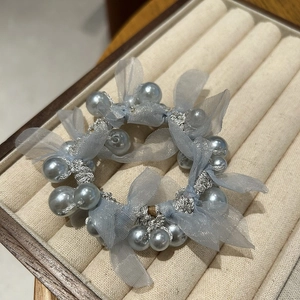 Detailed view of light blue pearl scrunchie with camellia mesh bow on a cream tray