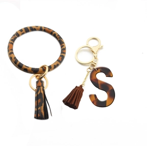 Detail of leopard print PU leather wristlet keychain with acrylic letter S and suede tassel