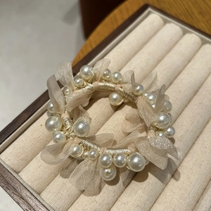 Detailed macro view of an elegant pearl scrunchie with ruffled mesh on a velvet jewelry tray