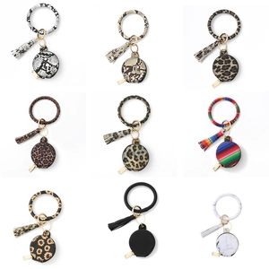 Détails des porte-clés en similicuir avec pochettes rondes et bracelets à pompons