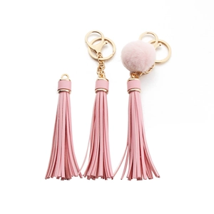 Pink PU leather tassel keychain with a soft pompom and golden lobster clasp on white background