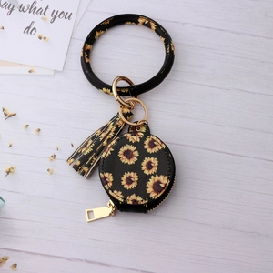 Gros plan d'un porte-monnaie rond à motif tournesol avec bracelet et gland doré chic