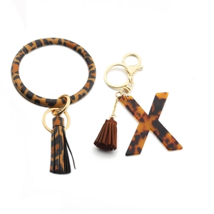 Detail of leopard print PU leather bangle with X acrylic pendant and gold key ring