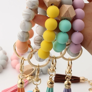 Detail of colorful silicone and wood bead wristlet keychain with leather tassel and gold clasp