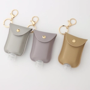 Three-piece leather hand sanitizer bottle holder set in grey and yellow with gold keychains