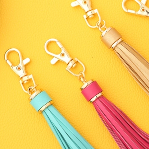 Colorful PU leather tassel keychains with gold metal lobster clasps on yellow background