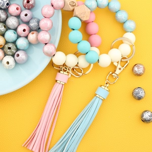 Detail of beaded key ring bracelet with printed wood beads and faux leather tassel